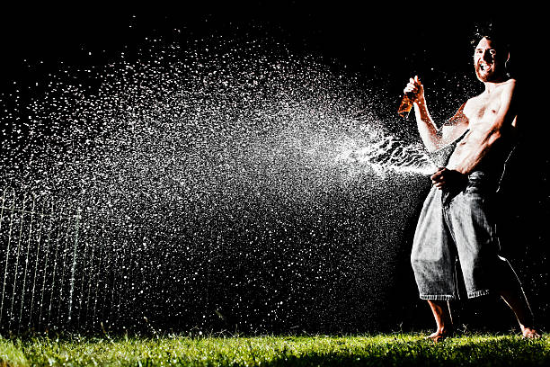 istock Man Drinking and Spraying Beer All Over Lawn at Night 108273575