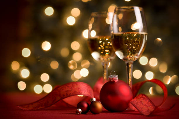 Red Christmas holiday wine in wine glasses with white lights in background.  Party atmosphere with Christmas ornaments, ribbons.  No people.  Wine tasting event or holiday party themes.