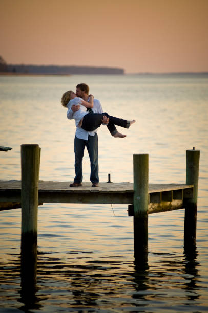 Young Couple Kiss on Lake Dock at Sunset stock photo