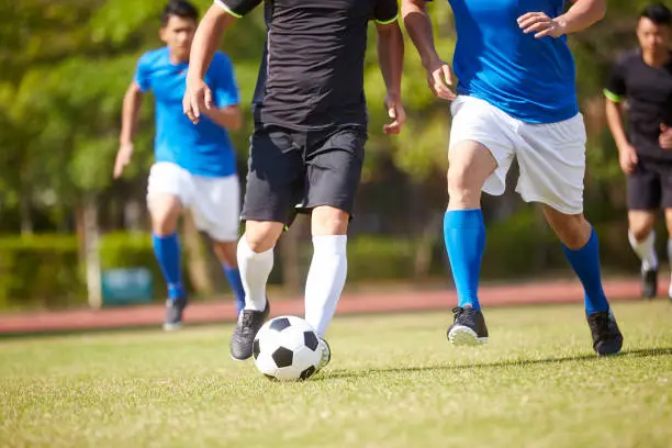 a group of young asian soccer football player playing on outdoor field.