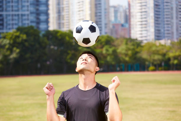 asian soccer football player practicing ball handling skill on outdoor field