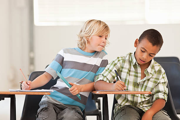 ragazzino peeping a compagni di classe esame di carta - decieve foto e immagini stock