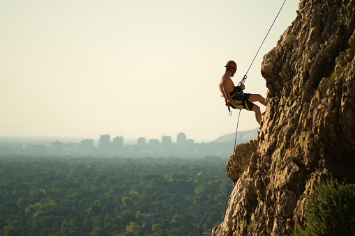Athletic old man climbing on overhanging cliff rock