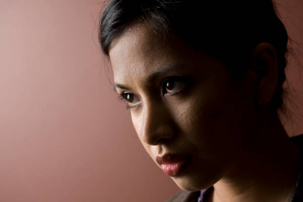 Beautiful young woman studio portrait wearing a orange colored bandana on a black background.