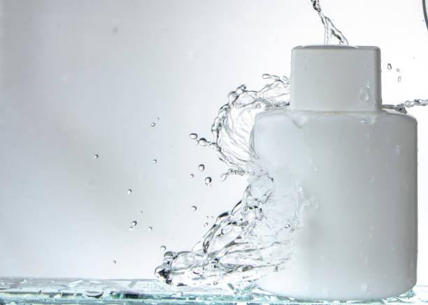 istock White square glass bottle on white background and splashing water 1082742394