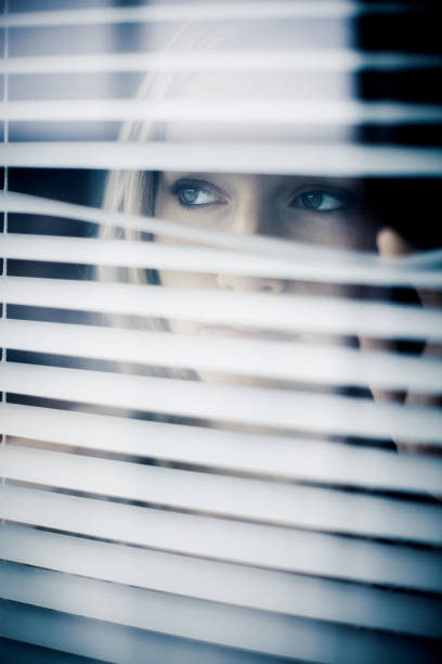istock Young Woman Looking Through Window Blinds 108274392
