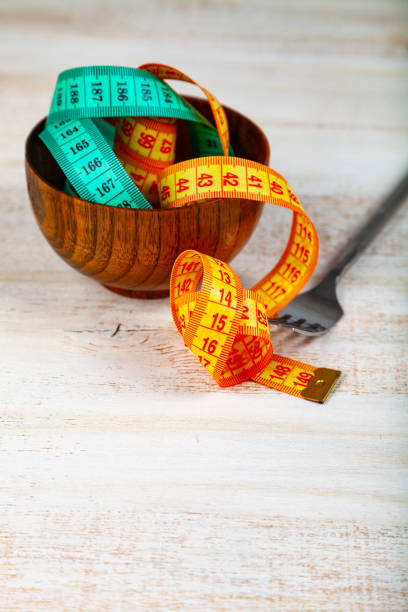 istock Measuring tape in a wooden bowl and fork. 1082746130