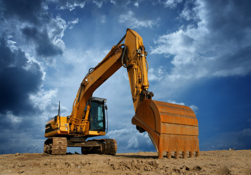 Front view of heavy duty yellow color excavator with shovel at sunny day.