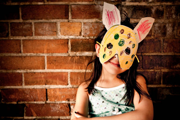 Little girl wearing paper bunny mask stock photo