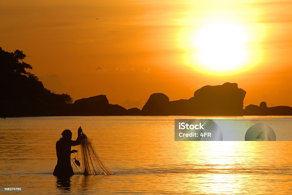 Pescador puxando silhueta ao nascer do sol em sua rede de pesca - Foto de stock de Peixe royalty-free