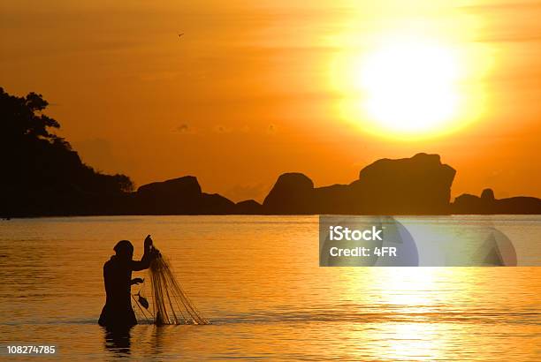 Foto de Pescador Puxando Silhueta Ao Nascer Do Sol Em Sua Rede De Pesca e mais fotos de stock de Peixe