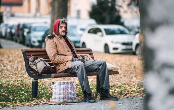 homme sans-abri mendiant avec un sac assis sur un banc à l’extérieur de la ville. copiez l’espace. - dirty bench empty park photos et images de collection