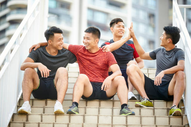 outdoor portrait of a team of four asian young athletes sitting on steps