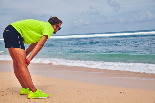 Sportsman stretching on a exotic tropical beach after jogging / exercising.