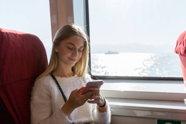 istock Young woman using smart phone in ferry 1082781922