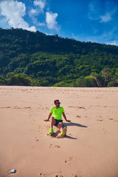 istock Sportsman stretching on a exotic tropical beach after jogging / exercising. 1082784282