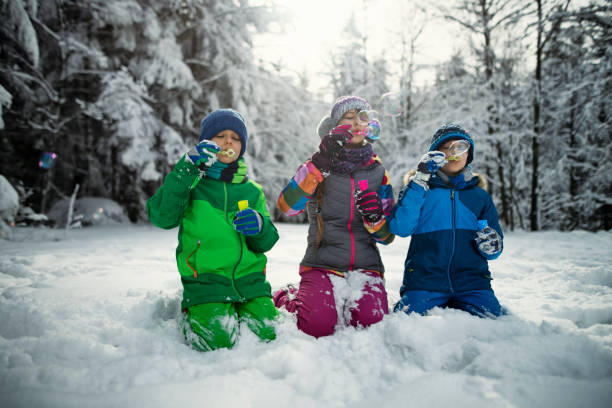 istock Kids blowing bubbles in winter forest 1082795912