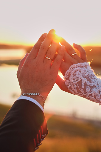 wedding couple hands touching fingers in the shape . Bright light of sun on background.