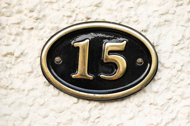 Gold Number 15 on cream pebble dash wall