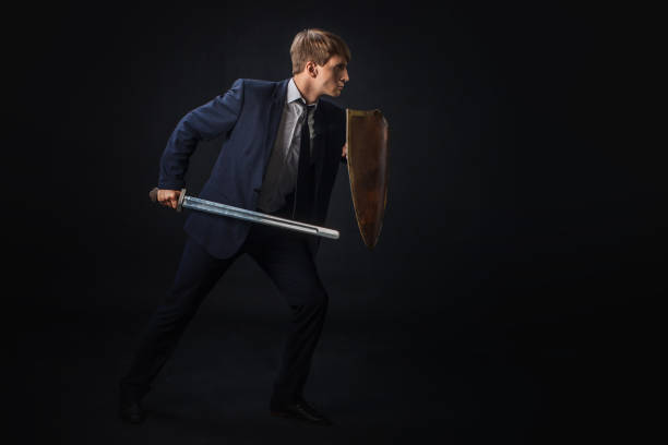 Businessman with shield and sword in the fighting rack, free space on the right. Anti-virus stock photo