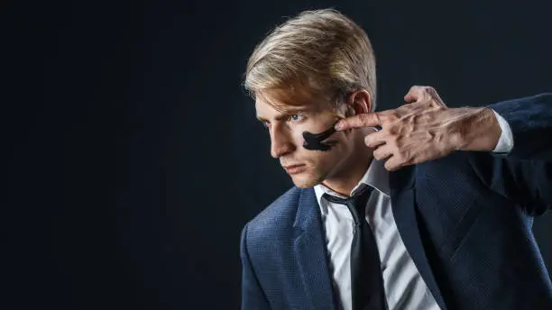 Businessman with war paint on his face. Risk management concept. young guy in suit with tie is preparing for a difficult job, make a war paint on the face
