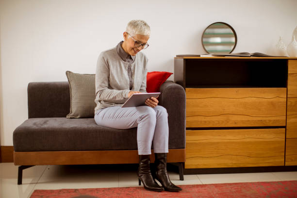 istock Senior businesswoman sitting with tablet on sofa 1082838272