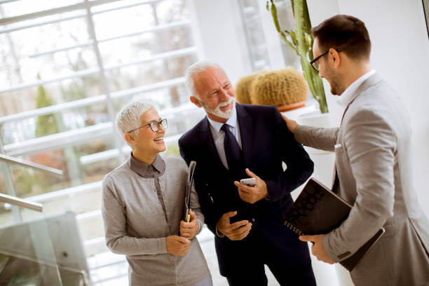 Young businessman with senior clients standing in office stock photo