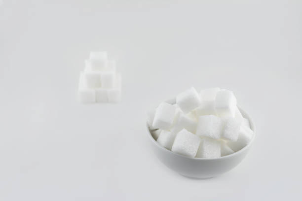 istock 0554_Sugar cubes in a white bowl, with a few sugar pieces stacked next to each other 1082847778