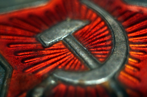 Hoz y el martillo soviéticos símbolos. En la antigua insignia de metal en rojo. photo