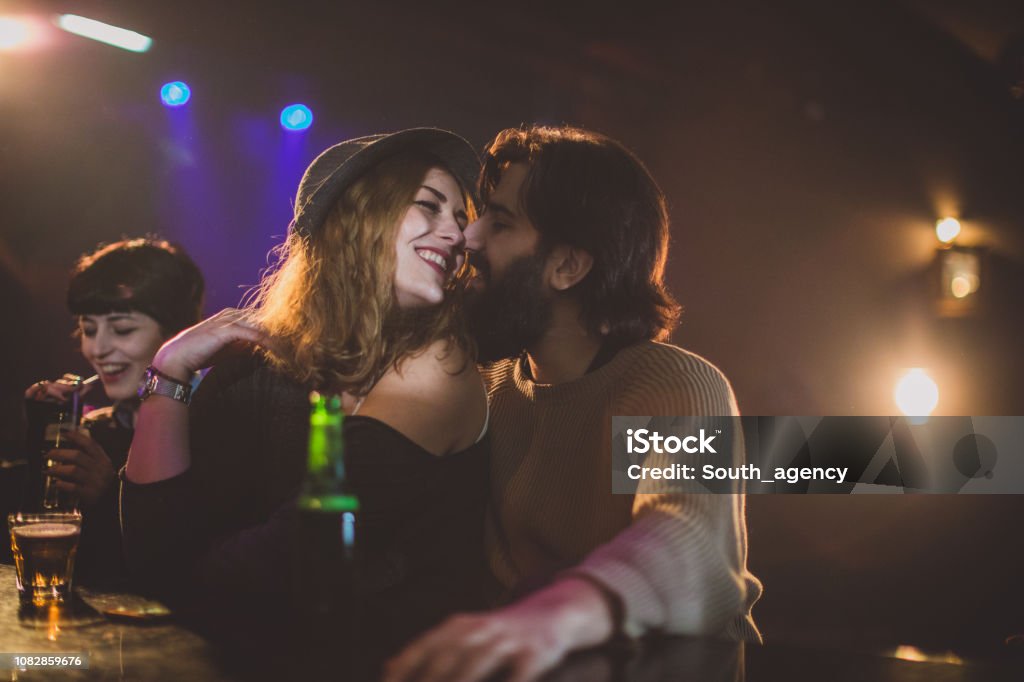 Party time Friends sitting on a bar counter in the night club and having a drink Couple - Relationship Stock Photo