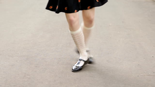 Dancer's legs close-up. Girl wearing white knee socks and black skirt dancing solo jazz swing dance.