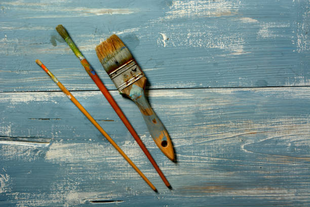 istock dirty paintbrushes on blue wooden table - closeup 1082866452