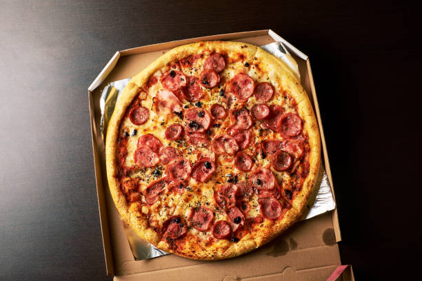 double cheese pizza from whole Pizza in a cardboard box dark table background.