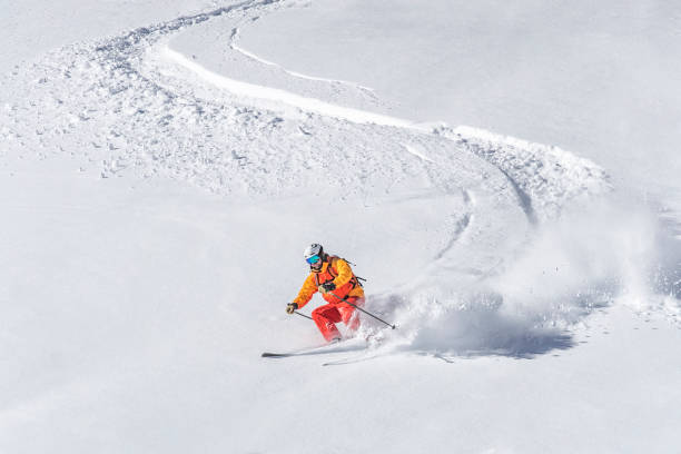 un esquiador freeride adultos esquí cuesta abajo a través de la nieve polvo profunda - skiing activity snow alpine skiing fotografías e imágenes de stock