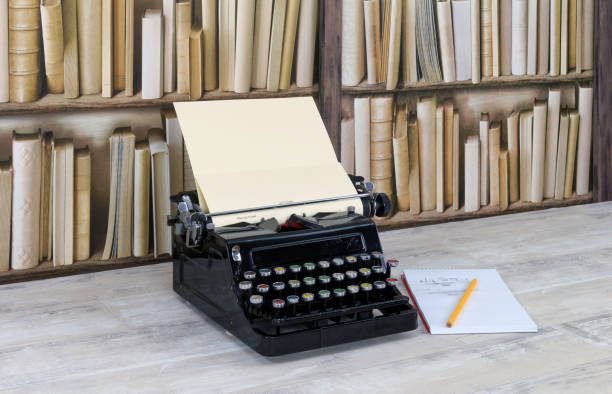 istock Vintage typewriter, notepad and pencil on old shabby wood effect desktop with old bookcase background 1082880140