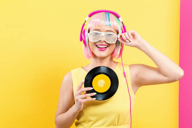 Woman in a colorful wig holding a vinyl record on a split yellow and pink background