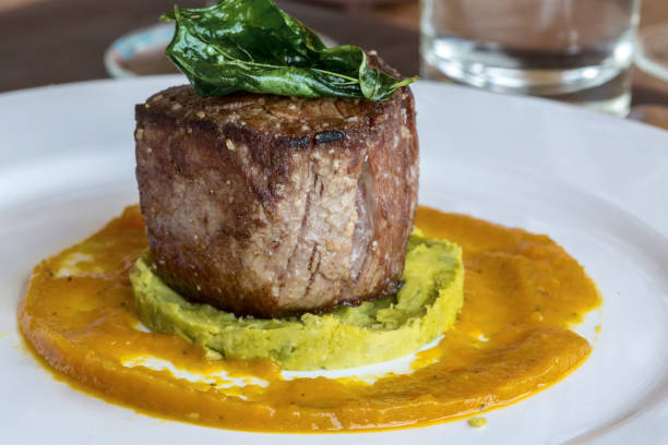 gros plan sur un steak de filet mignon sur un plateau blanc avec pois et courge musquée vue partielle d’une purée de fourche - steak argentina food silverware photos et images de collection