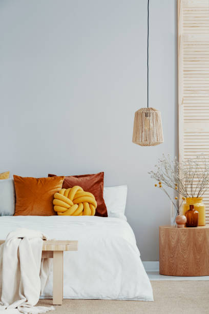 istock Yellow knot pillow on white bed in bright bedroom with copy space on empty white wall 1082907950