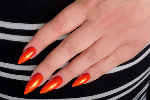 Orange stiletto manicure on striped dress