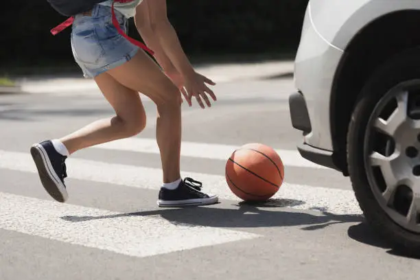 Photo of Young girl catching a basket ball on a pedestrian crossing