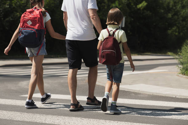istock Father crossing a street with his kids while coming back from school 1082911756