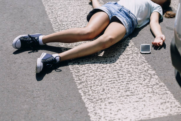 彼女の携帯電話の横に路上に横たわって意識不明の少女 - 気絶する ストックフォトと画像