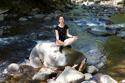 Beautiful girl meditates sitting on a stone. Relaxation.