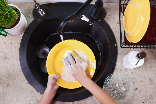 Child hands washing yellow plates at the kitchen sink Child hands washing yellow plates at the kitchen sink - doing the dishes, top view washing dishes photos stock pictures, royalty-free photos & images