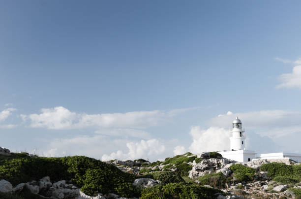 Traditional white light house in a sunny day in Cap Cavallería, Menorca, Balearic Islands, Spain. stock photo