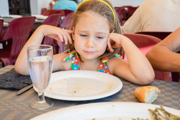 istock little girl looking with sad expression face at a plate with fish cooked 1082937344