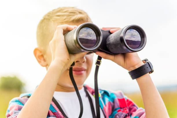 istock Young boy looking through binoculars, outdoors 1082944922