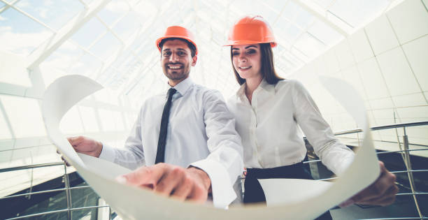 istock The two smile builders in a helmets hold the project plan in the building 1082948762