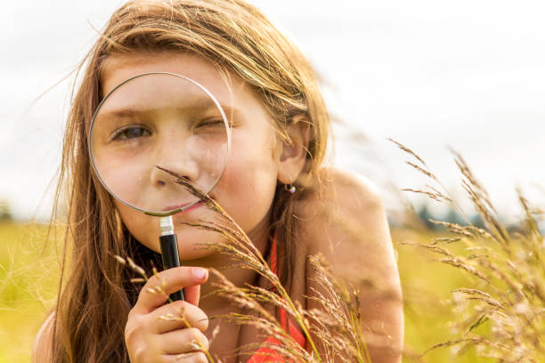 istock Girl playing in a meadow with a magnifier 1082949740