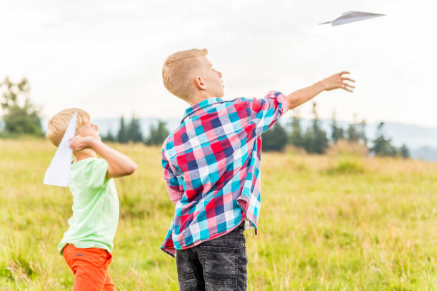 istock Boys playing with paper airplanes in a meadow 1082954970